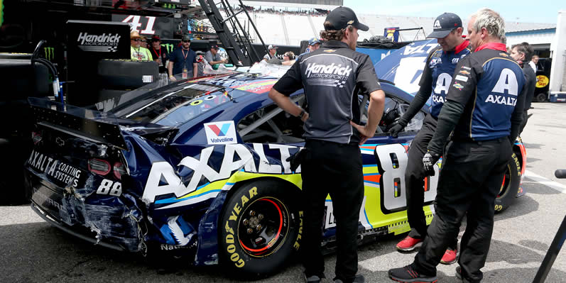 Crew members work on the damaged car of Alex Bowman