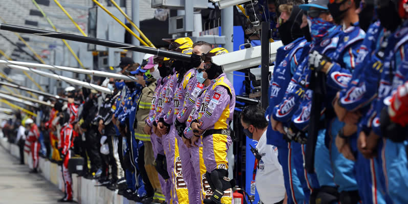 Crew members pause and stand on pit wall