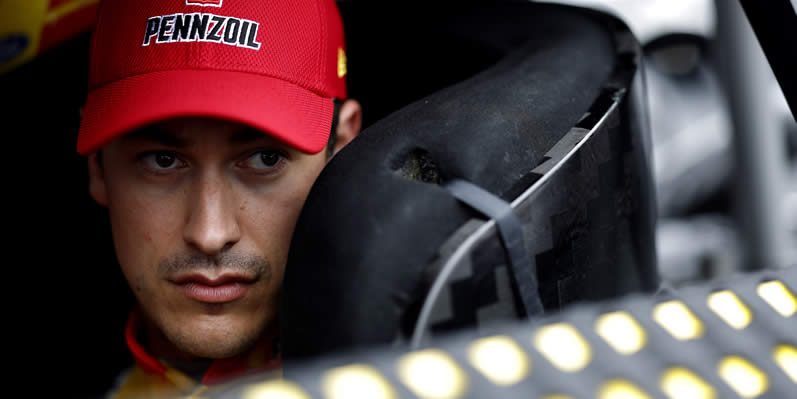 Joey Logano sits in his car during practice