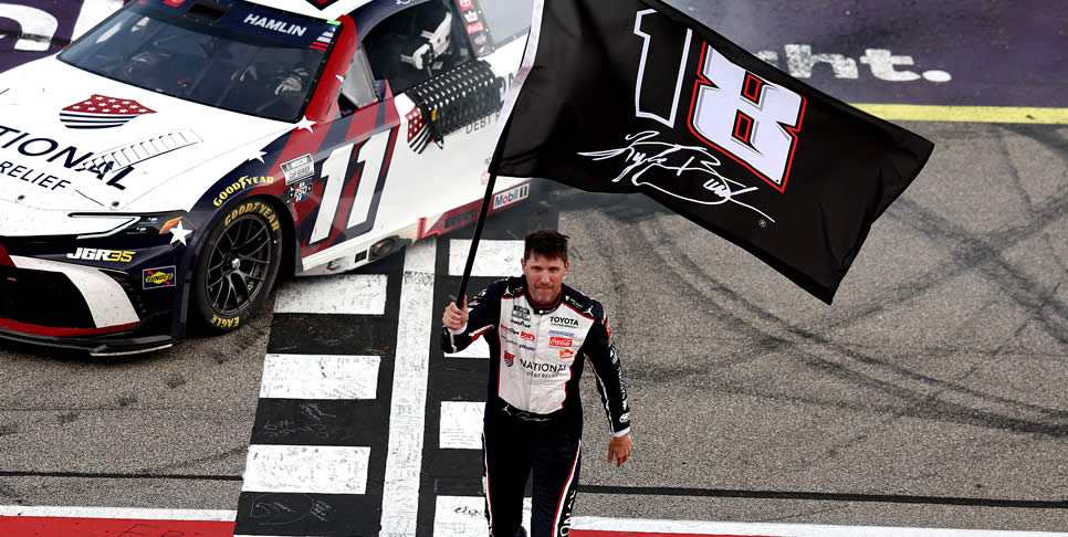Denny Hamlin waves an 18 - 8 flag in honor of the late Kyle Busch